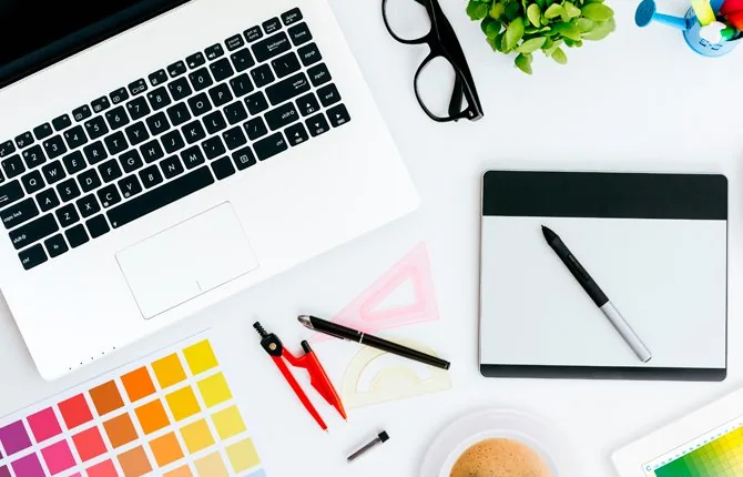 Mesa de trabajo con notebook, muestras de color y herramientas de diseño